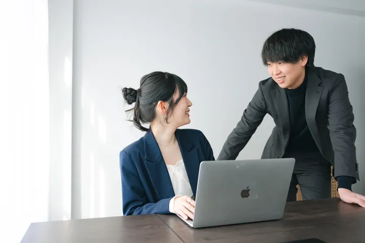 ノートパソコンを前に女性と笑顔で向き合う、株式会社AccelaLink代表の草薙さん